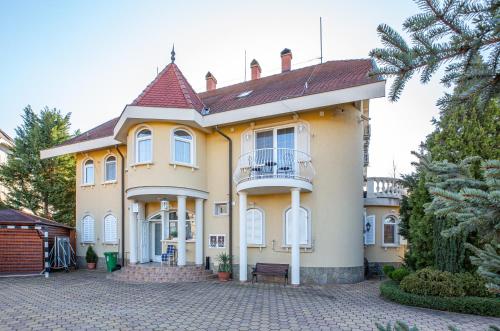 a large yellow house with a balcony at Villa Rosa in Hajdúszoboszló