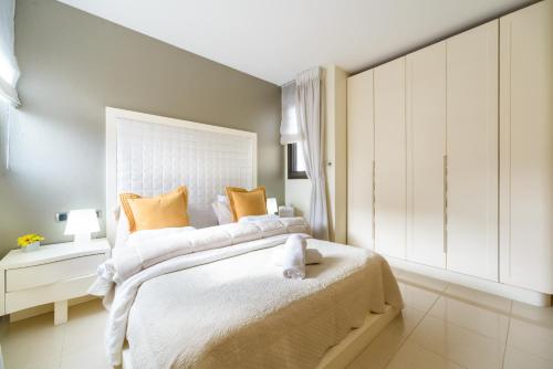una camera da letto con un grande letto bianco con cuscini arancioni di Comfort 3BR Apt with Balcony near Beach by FeelHome a Tel Aviv