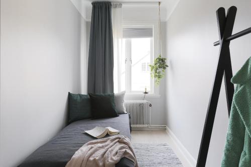 Habitación con cama con libro y ventana en Linne Apartment, en Uppsala