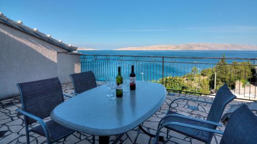 - une table avec des bouteilles de vin et des chaises sur le balcon dans l'établissement Senj Apartment, à Senj