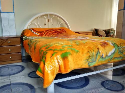 a bed with an orange blanket on top of it at habitación privada y confortable in La Paz