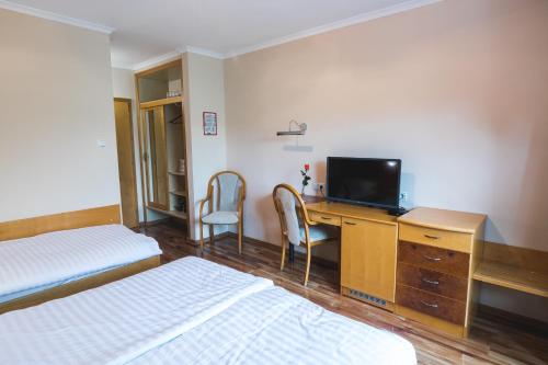 a hotel room with two beds and a desk with a television at HOTEL SMUK in Semič