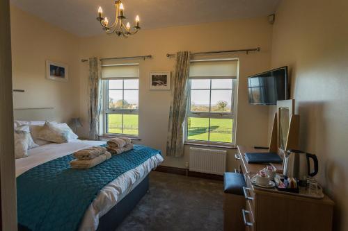 a bedroom with a bed and a television and windows at Glendaloch B&B in Antrim