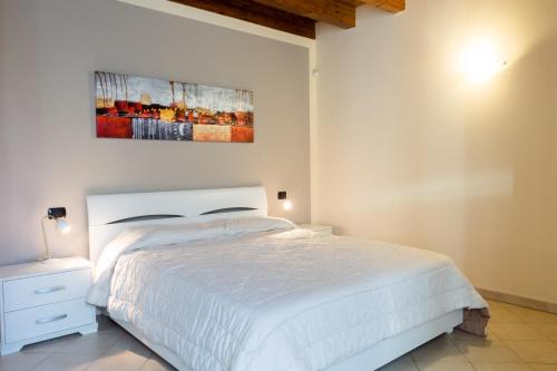 a bedroom with a white bed and a painting on the wall at Casa Lorena in Desenzano del Garda