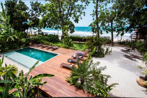 an outdoor swimming pool with lounge chairs and the beach at Flat Pitanga in Camburi