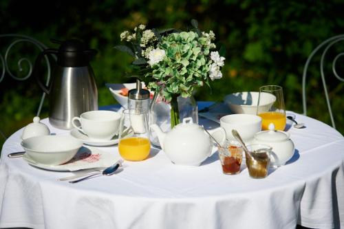 Rigny-UsséにあるDomaine de la Juranvillerie, gîte et chambres d'hôtesの白いテーブルクロスと花瓶が置かれたテーブル