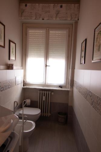 a bathroom with a toilet and two sinks and a window at Appartamento Santa Rita in Vigevano