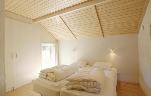 a bed in a room with a wooden ceiling at Nice Home In Aakirkeby With House Sea View in Vester Sømarken