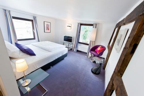 a bedroom with a white bed and a purple chair at Hotel Essgold in Ratingen