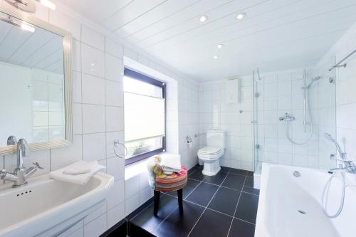 ein Badezimmer mit einer Badewanne, einem WC und einem Waschbecken in der Unterkunft Hotel Essgold in Ratingen