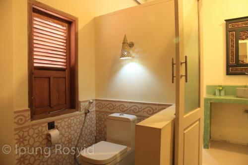 a bathroom with a toilet and a window and a light at Villa Diamond in Yogyakarta