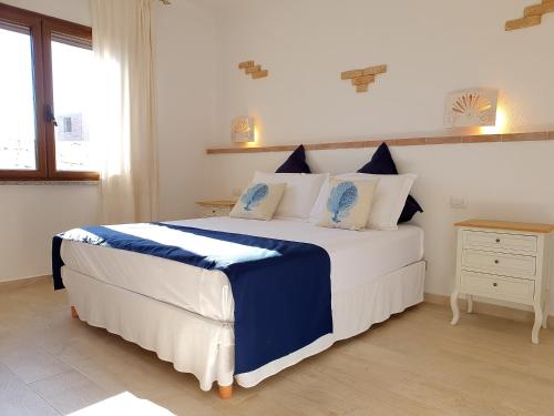 una camera da letto con un grande letto con cuscini blu e bianchi di Villino Turchese Budoni a Budoni