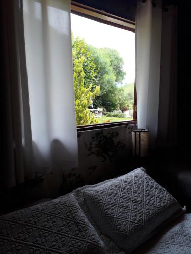 a bedroom with a bed and a window at Pousada Refugio Sol e Brisa in São Bento do Sapucaí