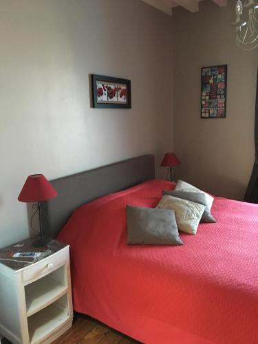 - une chambre avec un lit rouge et une table de chevet avec deux lampes dans l'établissement la p'tite maison, à Feuguerolles-sur-Orne