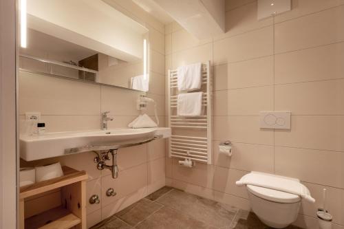 a white bathroom with a sink and a toilet at Hotel Hauserwirt in Münster