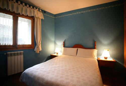 Can Janpere I في Pardines: غرفة نوم مع سرير بجدران زرقاء ومصباحين