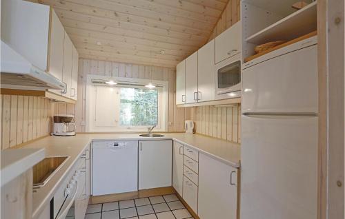 a kitchen with white cabinets and a white refrigerator at Holiday Home Turistvej Nexø in Snogebæk
