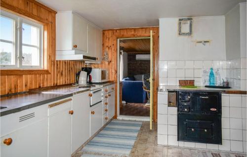 a kitchen with white cabinets and a black stove at Awesome Home In Ambjörnarp in Ambjörnarp