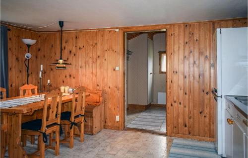 a kitchen with wooden walls and a table and a refrigerator at Awesome Home In Ambjörnarp in Ambjörnarp