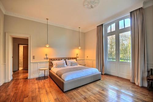 a bedroom with a bed and a large window at Château de la Bribourdière in Putot-en-Auge