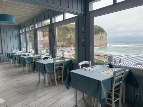 a restaurant with tables and a view of the ocean at Hôtel La Sirène in Yport