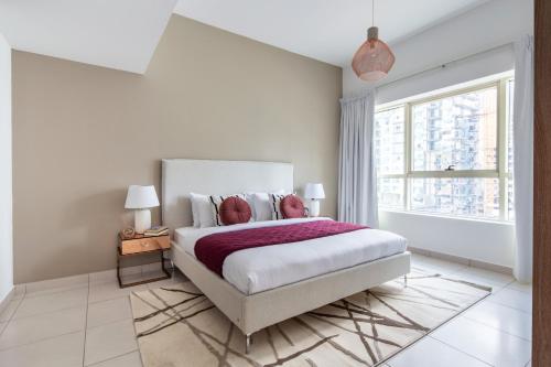 a white bedroom with a large bed and a window at Frank Porter - Marina View Tower in Dubai