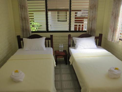 two beds in a small room with a window at Cameron Island Resort in Ko Sukon