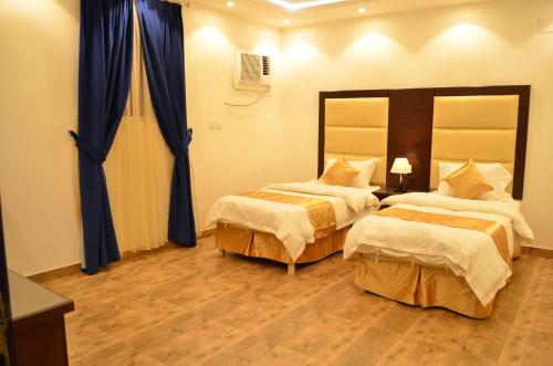 a hotel room with two beds and blue curtains at شقق برج الشمال للشقق المخدومة Burj Alshmmal serviced apartments in Tabuk