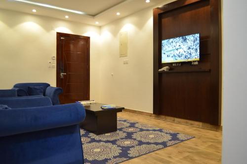 Sala de espera con sillas azules y TV de pantalla plana en برج الشمال للشقق الفندقية Burj ALShamal, en Tabuk