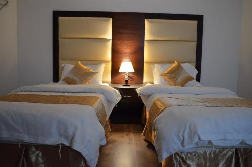 a hotel room with two beds and a lamp on a table at شقق برج الشمال للشقق المخدومة Burj Alshmmal serviced apartments in Tabuk