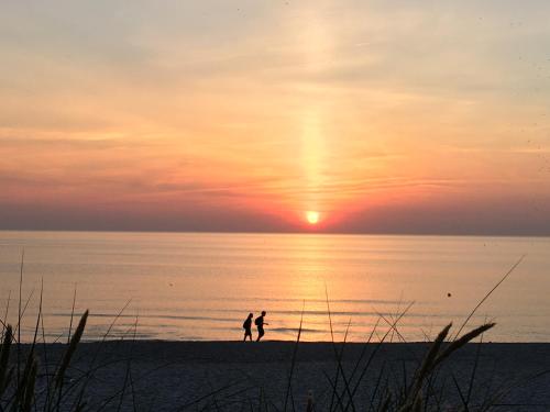 two people walking on the beach at sunset at Curonian Coast studio in Nida