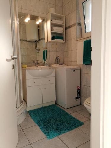 a bathroom with a sink and a toilet and a rug at La Petite Maison in Splitska