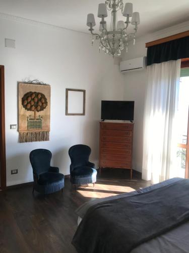 a bedroom with a bed and two chairs and a television at La Casa di Anna in Siderno Marina
