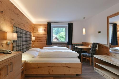 una camera con due letti, un tavolo e una finestra di Hotel Garni Vanadis a Ortisei