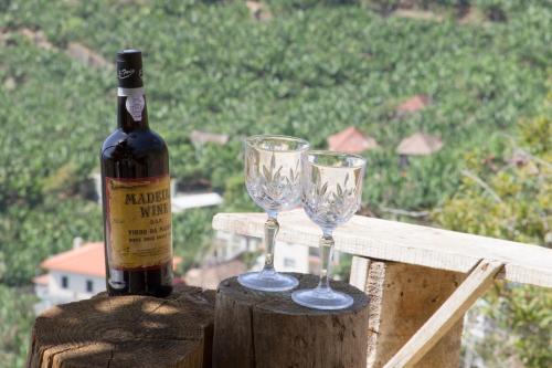 a bottle of wine and two wine glasses on a rail at Tabua Village Madeira Suite 5 Nature Lovers in Ribeira Brava