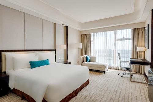 a hotel room with a large white bed and a desk at Junluxe Hotel Guangzhou Zengcheng-Free Shuttle Bus For Canton Fair in Zengcheng