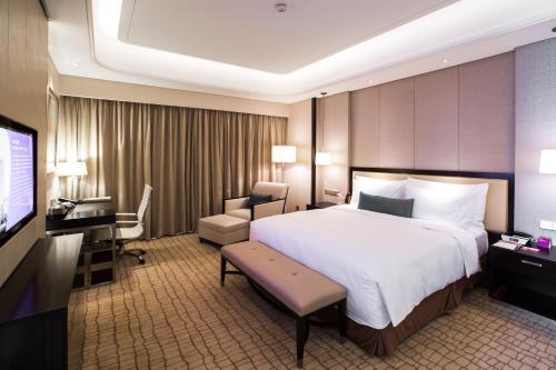 a hotel room with a large bed and a television at Junluxe Hotel Guangzhou Zengcheng-Free Shuttle Bus For Canton Fair in Zengcheng