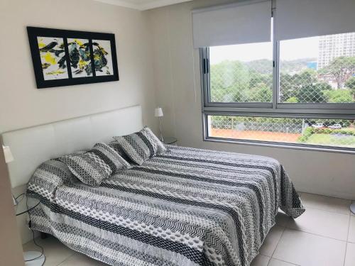 1 dormitorio con 1 cama con manta y ventana en Cómodo apartamento en Torre Ocean Drive con todos los servicios, en Punta del Este