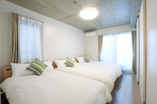 three white beds in a room with a window at Laffitte Tokyo WEST in Tokyo