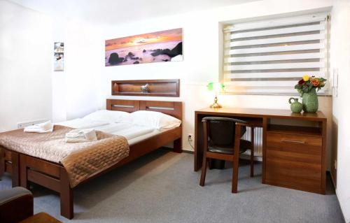 a bedroom with a bed and a desk and a desk at Penzion Troja in Lipany