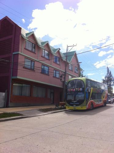 a bus driving down a street in front of a building at Hotel Saltos del Paine in Puerto Natales