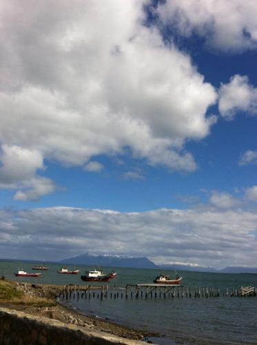 a group of boats on the water under a cloudy sky at Hotel Saltos del Paine in Puerto Natales