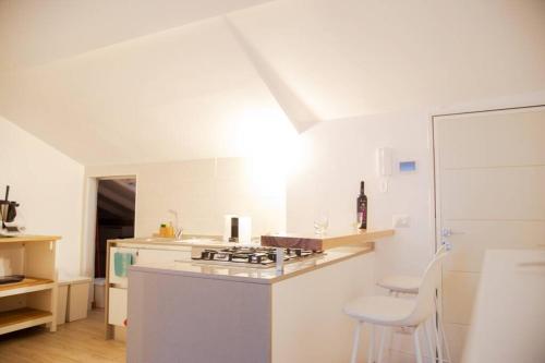 a white kitchen with a stove and a counter top at Casa Valastro in Aci Castello