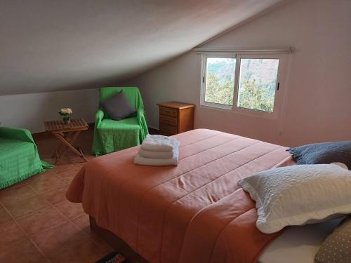 a bedroom with a bed and two green chairs at Tabua Village Adventure Room #6 with Ocean View in Ribeira Brava