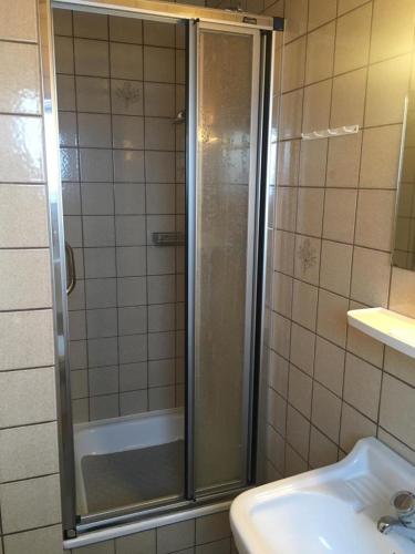 prysznic ze szklanymi drzwiami obok umywalki w obiekcie Kiekkast 3 w mieście Norddeich