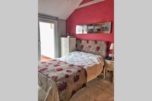 - une chambre avec un lit et un mur rouge dans l'établissement Duplex, terraza, 10 min coche centro Sevilla, à Camas