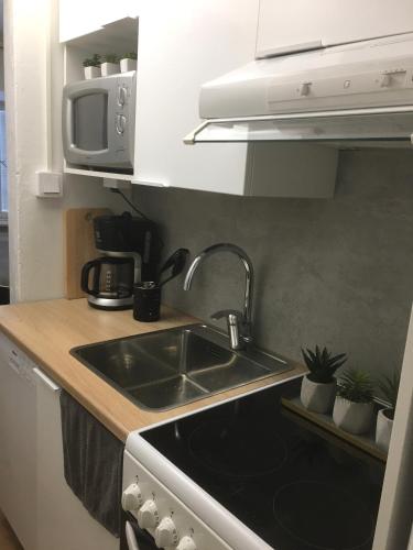a kitchen with a sink and a microwave at StarHomes Hallituskatu 23 in Oulu