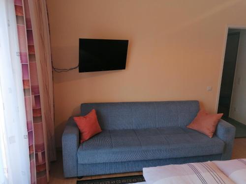 sala de estar con sofá azul y TV en la pared en Ferienhaus Mattersberger, en Oberlienz