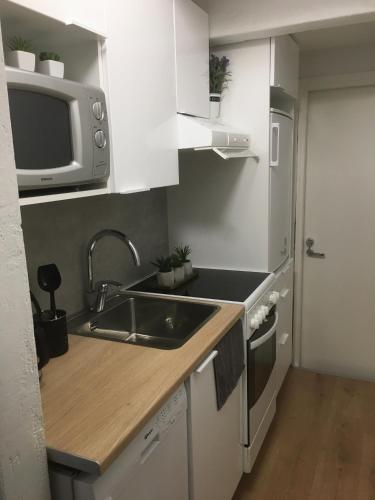 a small kitchen with a sink and a microwave at StarHomes Hallituskatu 23 in Oulu