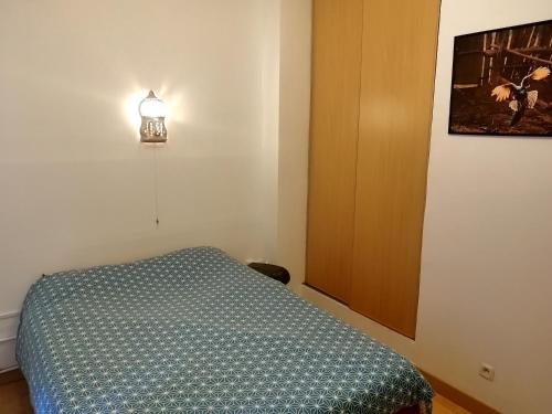 a bedroom with a bed and a light on the wall at Appartement T2 Hyper City Centre in Le Mans